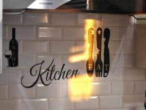 Kitchen wall decor with utensils and wine bottle.